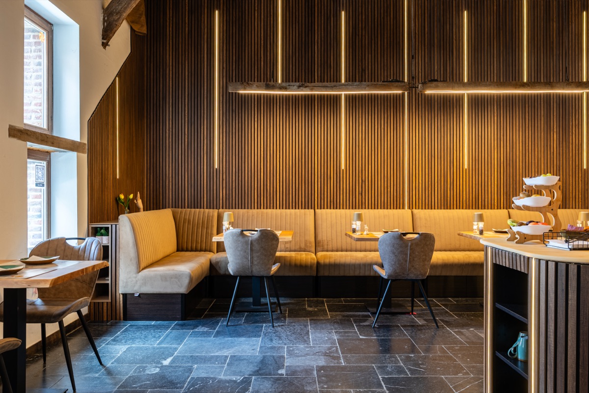 Ontbijtruimte met warme houten lattenwand en zitbanken — bed and breakfast Massemen