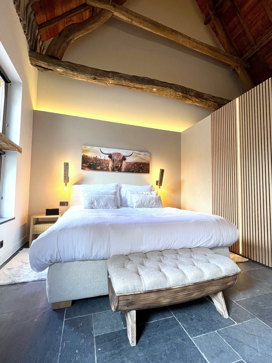 De Villaine bed onder dakbalken — luxe overnachten Massemen